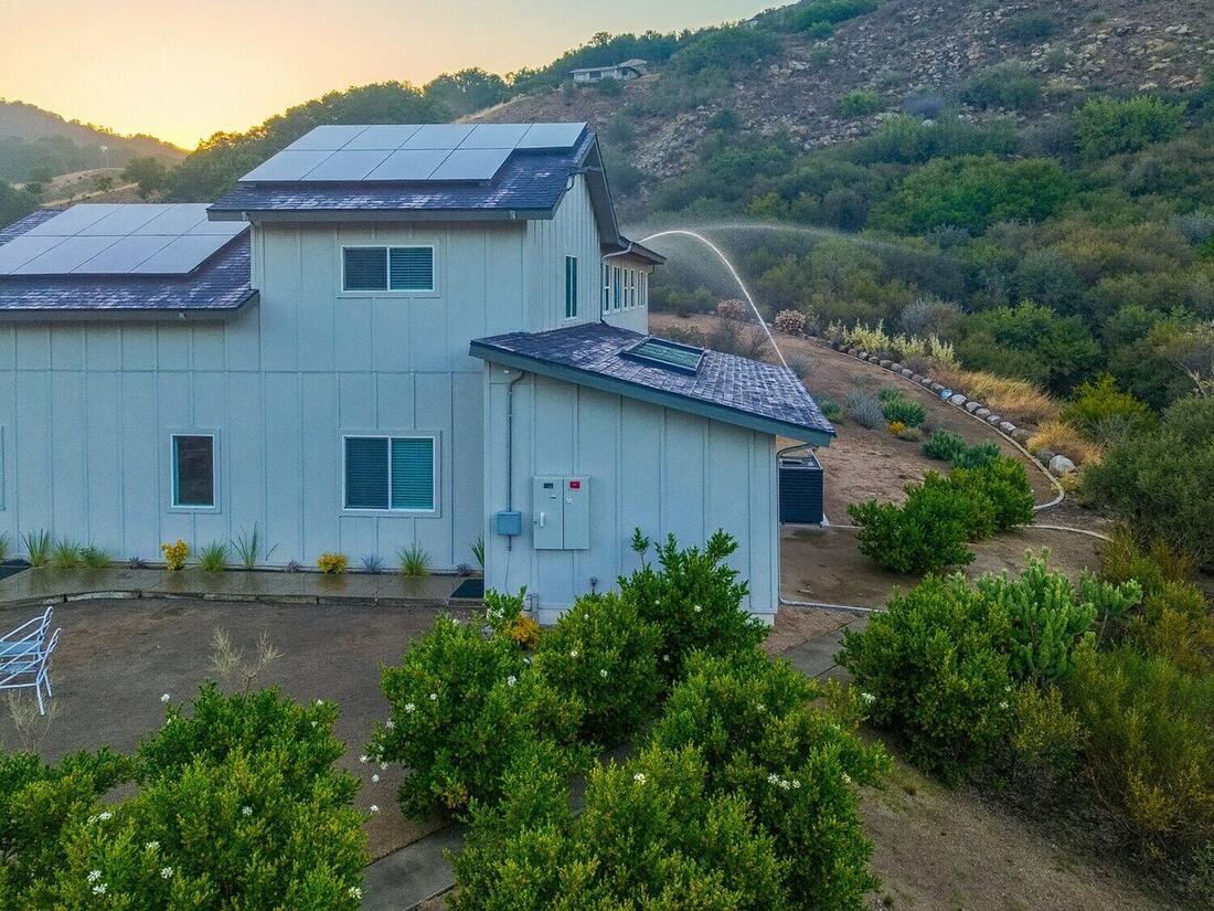 Rooftop sprinkler spraying at golden hour on a hillside home